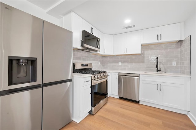 kitchen featuring stainless steel appliances, light wood-style flooring, a sink, and light countertops