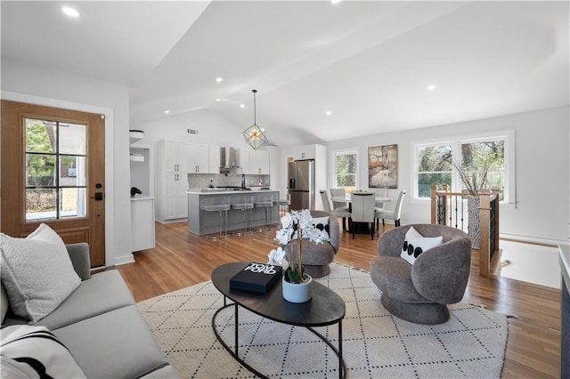 living room with recessed lighting, vaulted ceiling, and light wood-style flooring