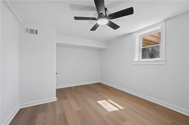 spare room with a ceiling fan, wood finished floors, visible vents, and baseboards