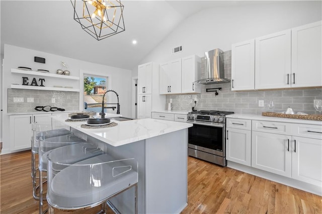 kitchen with open shelves, visible vents, a sink, gas range, and wall chimney exhaust hood