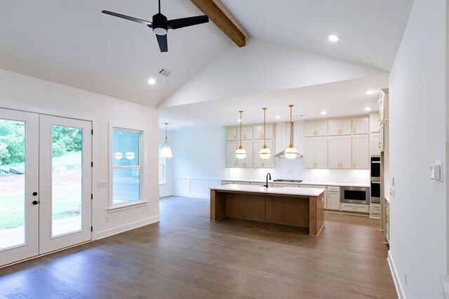 kitchen featuring french doors, pendant lighting, beam ceiling, dark hardwood / wood-style floors, and an island with sink