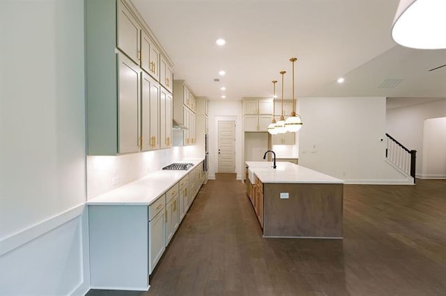 kitchen with pendant lighting, a kitchen island with sink, dark wood-type flooring, sink, and stainless steel gas cooktop