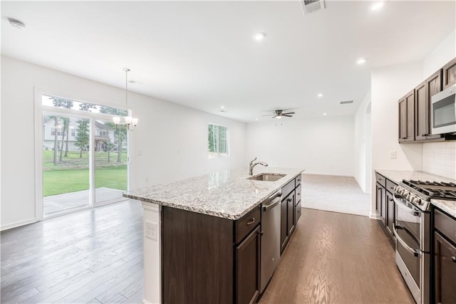 kitchen with a wealth of natural light, stainless steel appliances, an island with sink, and dark hardwood / wood-style floors