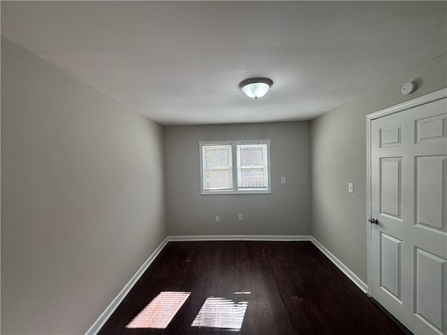 empty room featuring dark wood finished floors and baseboards