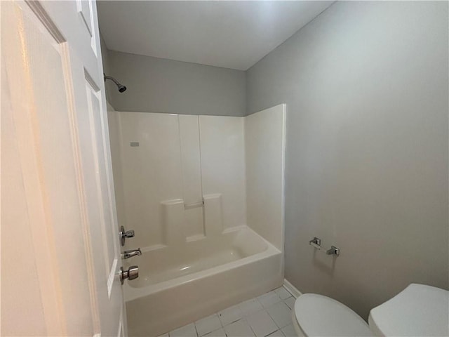 bathroom featuring tile patterned flooring, baseboards, tub / shower combination, and toilet