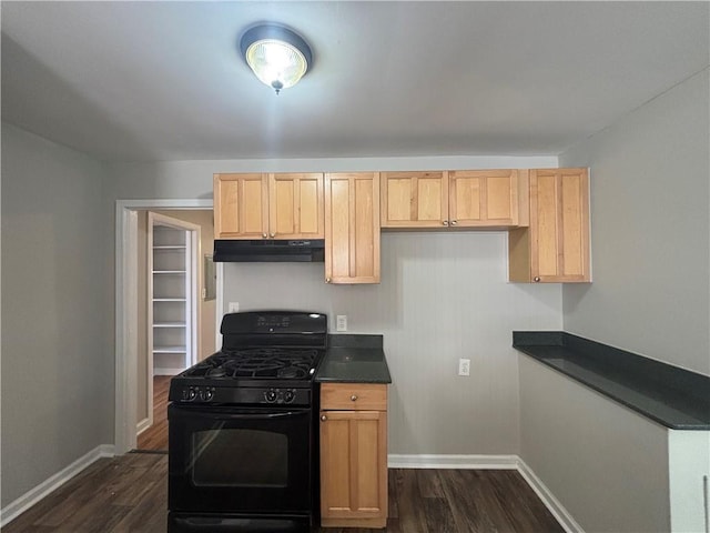 kitchen with black gas range, dark countertops, under cabinet range hood, and dark wood-style flooring