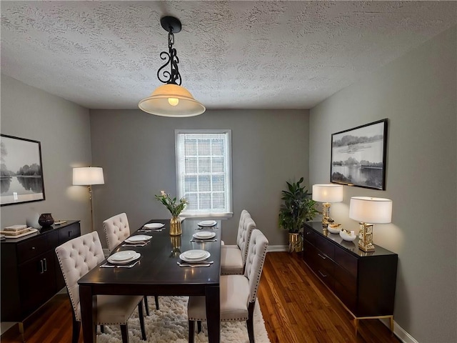 dining space with a textured ceiling, baseboards, and dark wood-type flooring