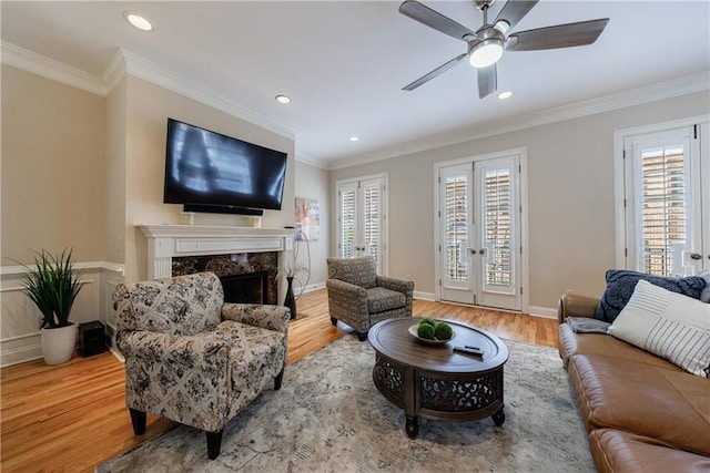 living area with a healthy amount of sunlight, wood finished floors, and ornamental molding