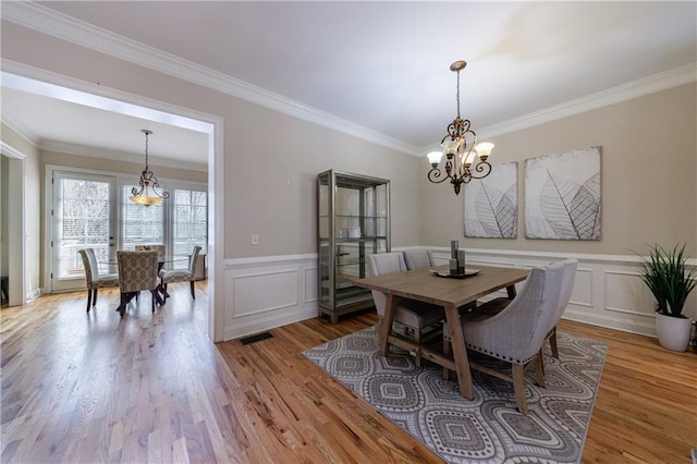 dining room featuring a notable chandelier, light wood finished floors, and ornamental molding