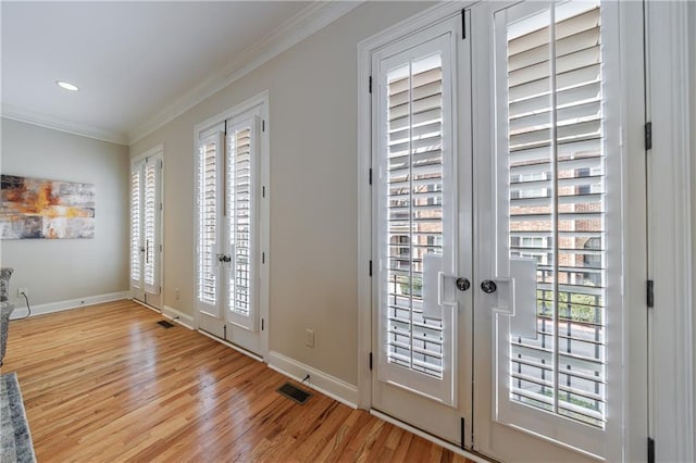 doorway featuring visible vents, french doors, light wood-style floors, crown molding, and baseboards