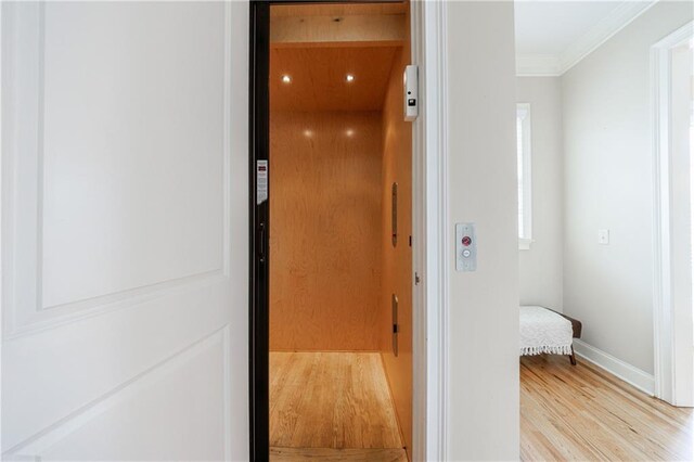 interior space featuring wood finished floors, baseboards, elevator, recessed lighting, and crown molding