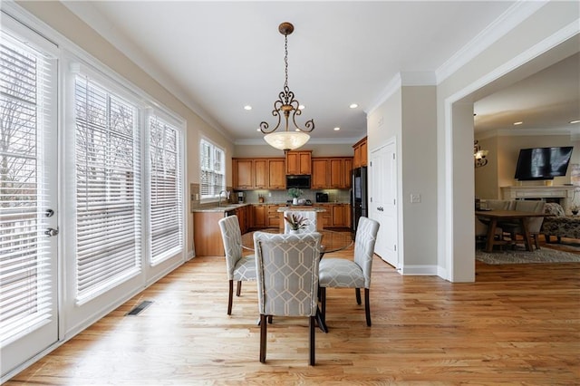 dining space featuring a notable chandelier, visible vents, light wood-type flooring, and ornamental molding