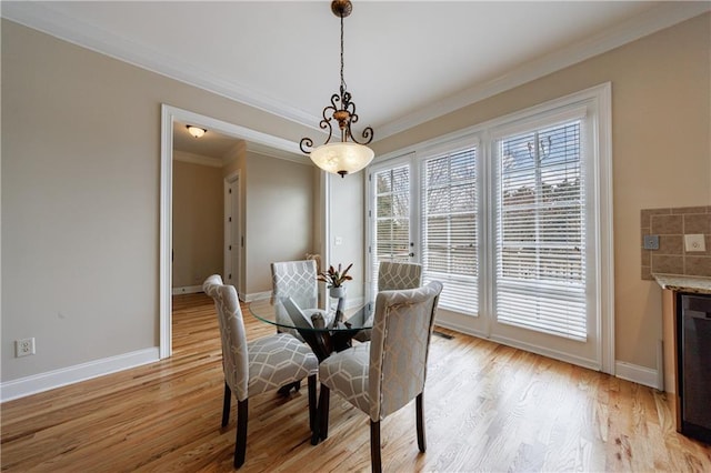 dining area featuring crown molding, baseboards, and light wood-type flooring