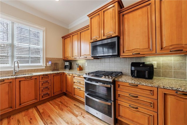 kitchen with brown cabinetry, ornamental molding, double oven range, and a sink