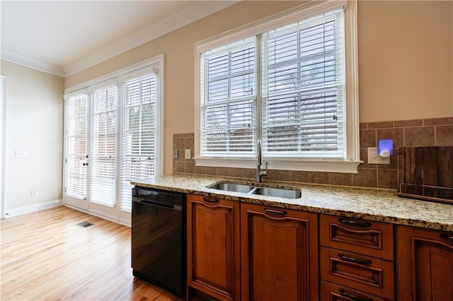 kitchen featuring light wood-style flooring, ornamental molding, a sink, light stone counters, and black dishwasher
