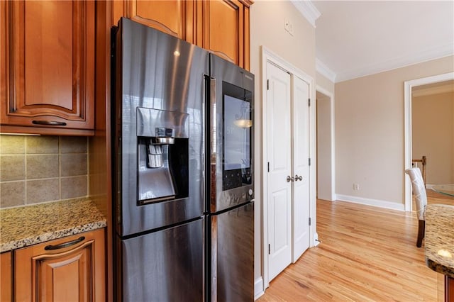 kitchen with brown cabinetry, backsplash, ornamental molding, and stainless steel refrigerator with ice dispenser