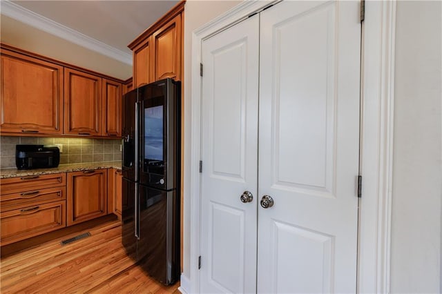 kitchen featuring visible vents, brown cabinets, light stone countertops, and ornamental molding