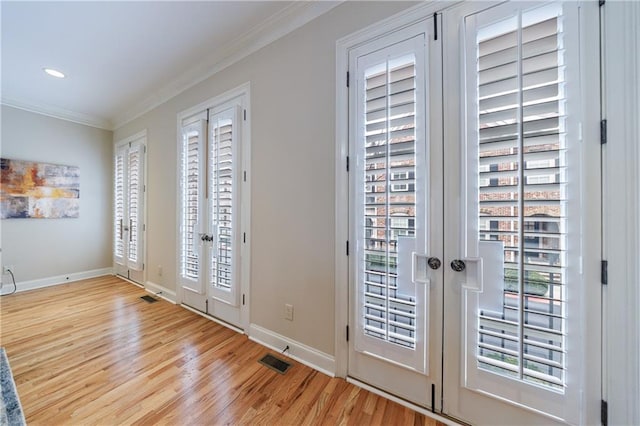 entryway featuring wood finished floors, french doors, visible vents, and ornamental molding