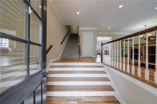 staircase featuring a chandelier, recessed lighting, crown molding, and wood finished floors