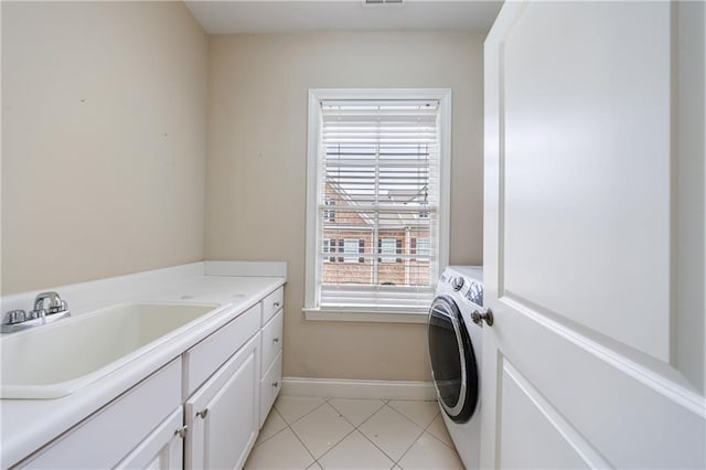 laundry area with visible vents, baseboards, light tile patterned floors, cabinet space, and a sink