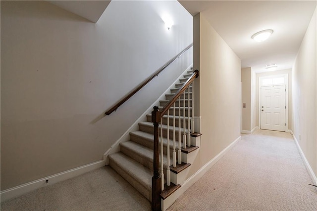 stairway featuring baseboards and carpet floors