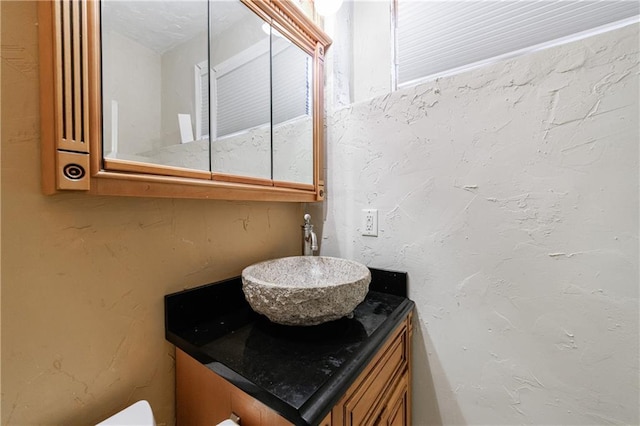 half bathroom featuring vanity and a textured wall