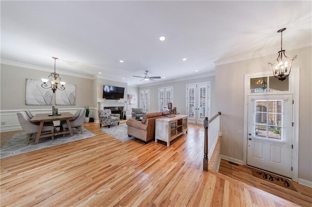 living area featuring a high end fireplace, recessed lighting, light wood-style flooring, and ornamental molding