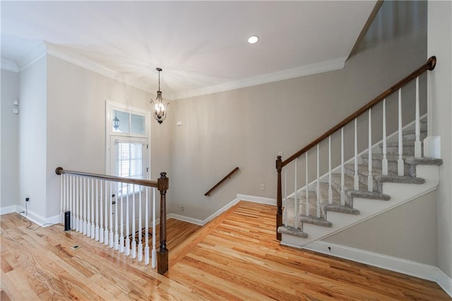 stairs with baseboards, an inviting chandelier, wood finished floors, and crown molding
