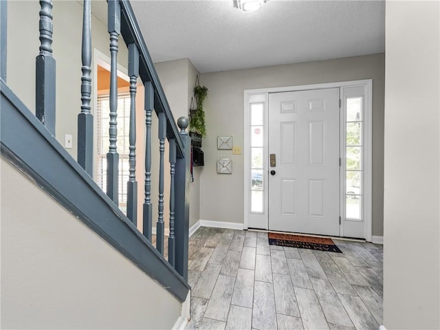 foyer entrance featuring a textured ceiling, hardwood / wood-style floors, and a wealth of natural light