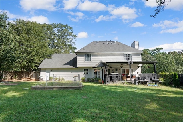 rear view of house with ceiling fan, a wooden deck, and a yard