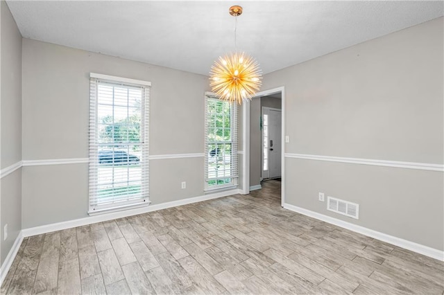 unfurnished room with a notable chandelier and light hardwood / wood-style floors