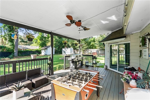 deck featuring ceiling fan, a grill, a shed, an outdoor hangout area, and a yard