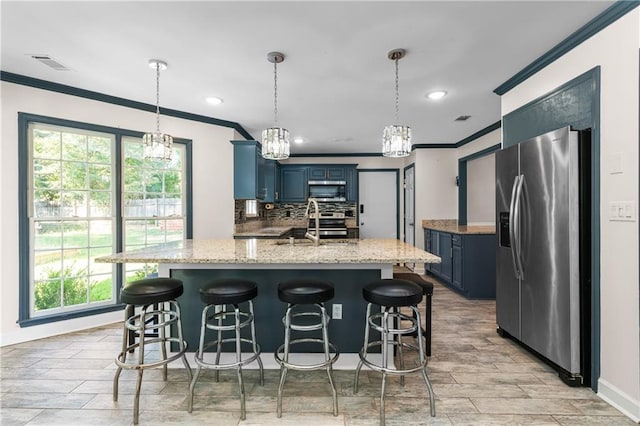 kitchen with blue cabinetry, a center island with sink, appliances with stainless steel finishes, and hanging light fixtures