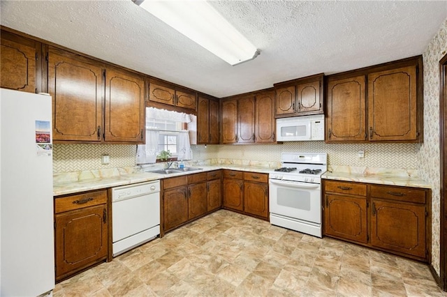 kitchen with sink, white appliances, a textured ceiling, and backsplash