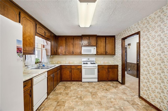 kitchen with sink, white appliances, and a textured ceiling