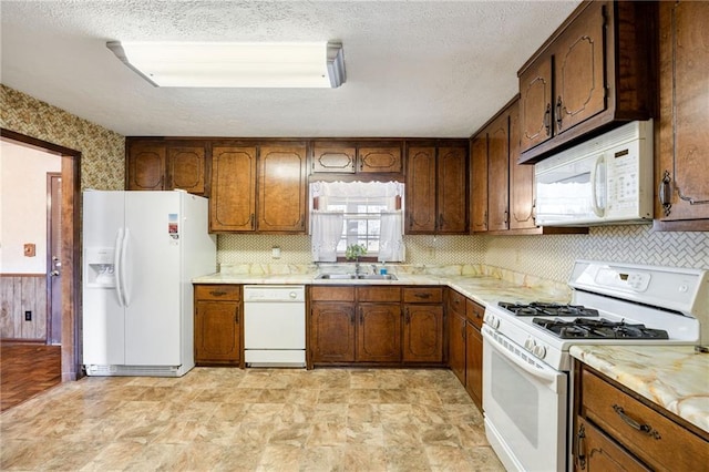 kitchen featuring tasteful backsplash, sink, white appliances, and a textured ceiling