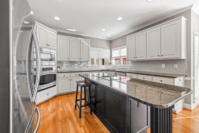 kitchen featuring dark stone countertops, stainless steel appliances, a breakfast bar, and white cabinets