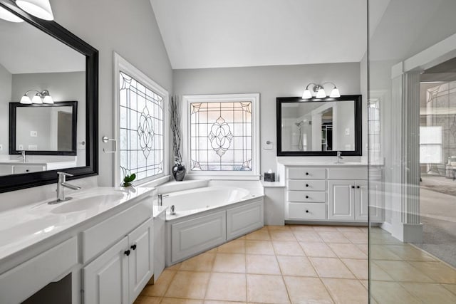 bathroom featuring vaulted ceiling, a bathtub, vanity, and tile patterned floors