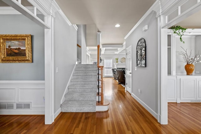 stairway with hardwood / wood-style flooring and crown molding