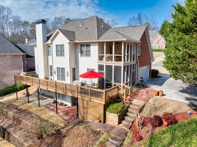 rear view of house featuring a patio, a balcony, a wooden deck, a garage, and a sunroom