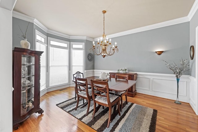 dining room with a notable chandelier, light hardwood / wood-style flooring, and ornamental molding