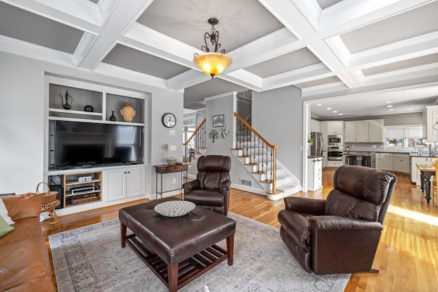 living room with coffered ceiling, beam ceiling, light hardwood / wood-style floors, and crown molding