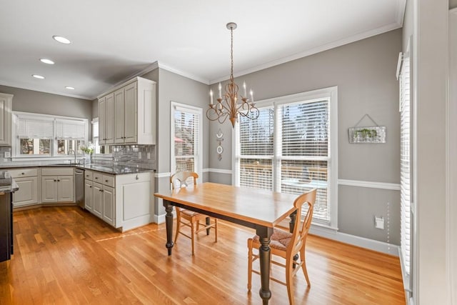 dining room with an inviting chandelier, sink, ornamental molding, and light wood-type flooring