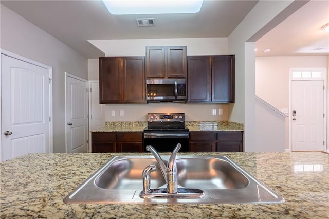 kitchen featuring light stone countertops, sink, stainless steel appliances, and dark brown cabinets