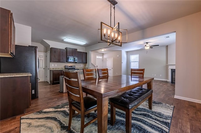 dining room with dark hardwood / wood-style flooring and ceiling fan with notable chandelier