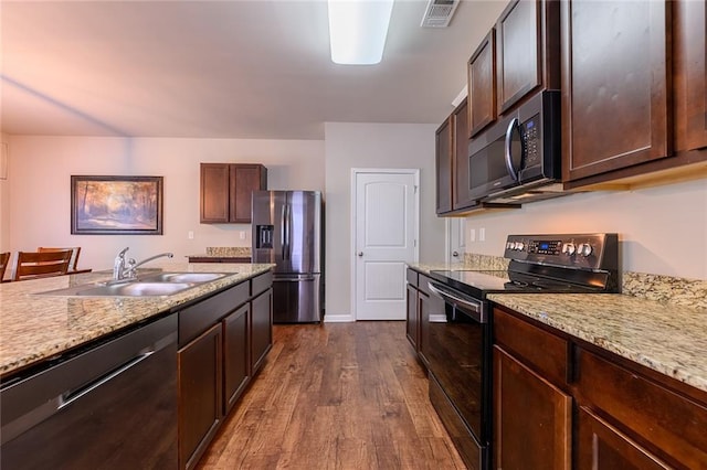 kitchen featuring light stone countertops, dark brown cabinets, stainless steel appliances, sink, and dark hardwood / wood-style floors