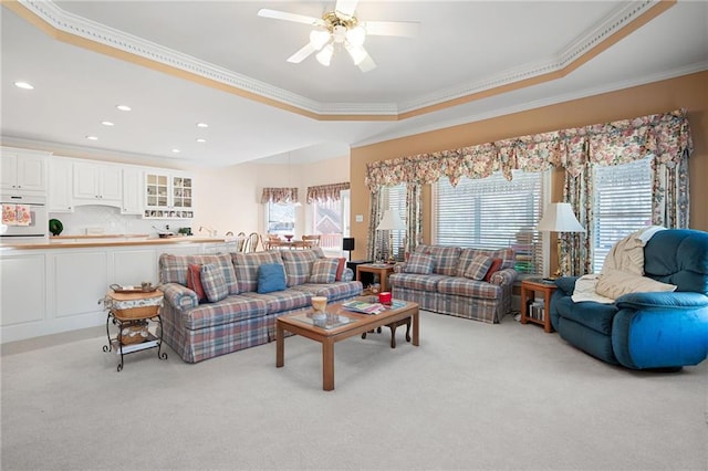 living area with recessed lighting, ornamental molding, a raised ceiling, and light colored carpet