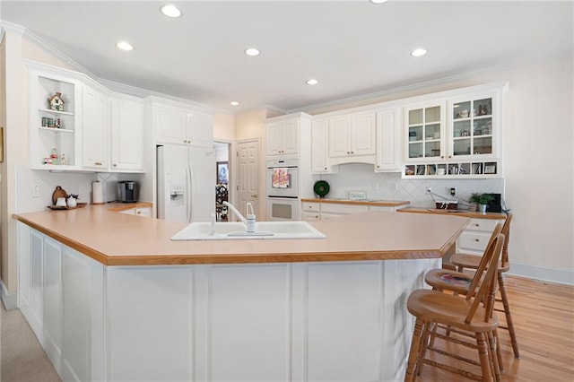 kitchen with white appliances, tasteful backsplash, a peninsula, open shelves, and a sink