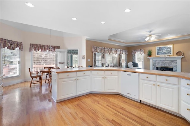 kitchen with crown molding, a fireplace, light wood finished floors, recessed lighting, and white dishwasher