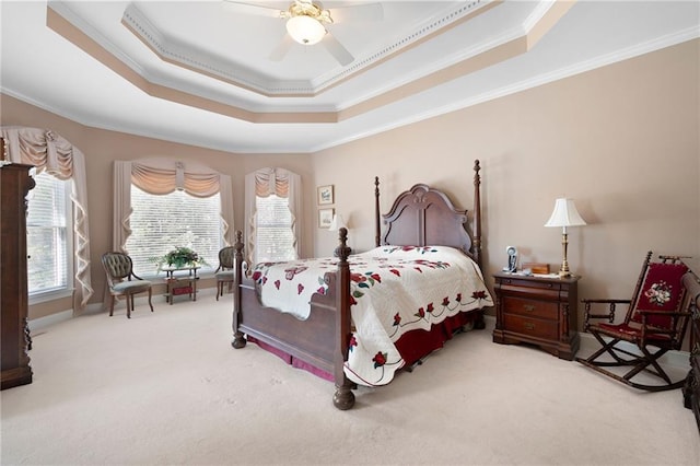 bedroom with a ceiling fan, a tray ceiling, carpet flooring, and crown molding